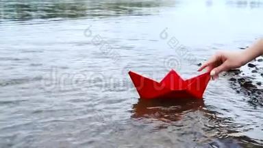 女人`手把红纸船放在水面上，把它推开